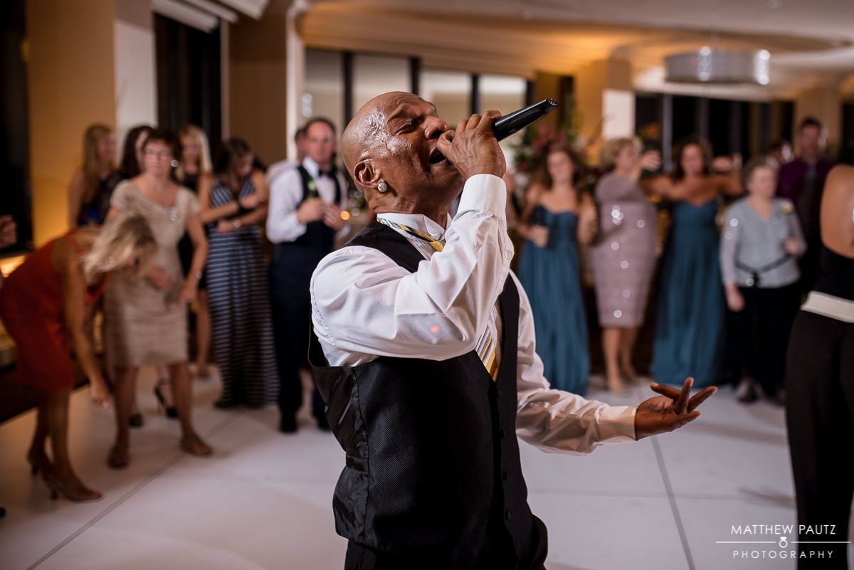 Flashback the Party Bands lead singer Dwane singing at a wedding reception surrounded by happy guests.