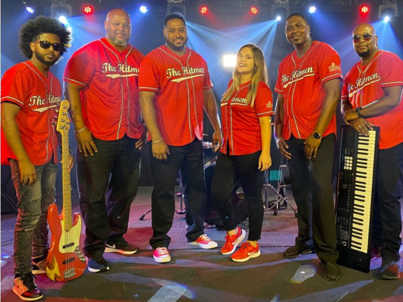 Six members of The Hitmen Party Band from South Carolina Posed for a Photo in Matching Red Custom Baseball Jerseys After a Video Shoot. When Hiring a Live Wedding Band The Hitmen are one of The Best in the Game.