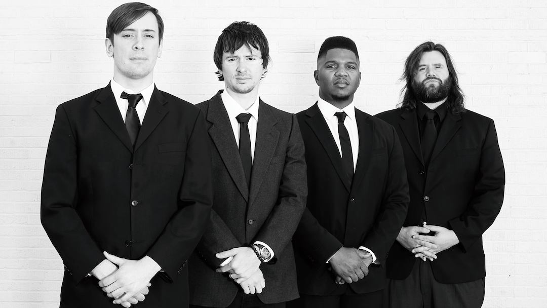 Members of the rock fusion band Reggie Sullivan Band post for a picture in black suits.